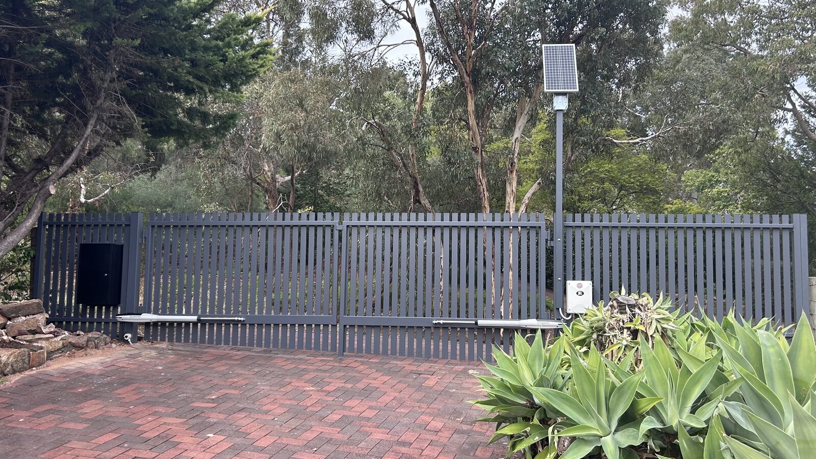 Vertical slatted double swing gate with solar powered automation